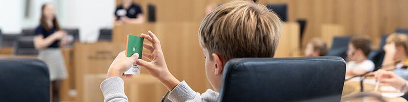 Im Zuge des Grundschulprogramms findet auch ein Planspiel im Plenarsaal statt. Ein Kind hält eine "Ja" Abstimmungskarte in der Hand.
